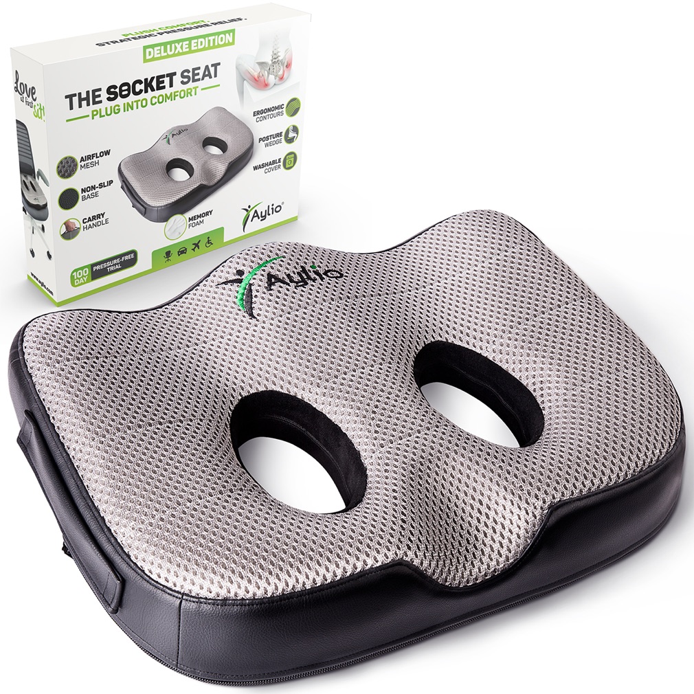 The Aylio Socket Seat cushion at a three-quarter angle, showing its two contoured sit-bone openings and airflow mesh top, beside its retail box.